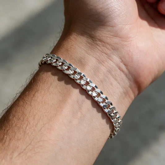 Silver diamond-cut flat curb chain bracelet worn on the wrist