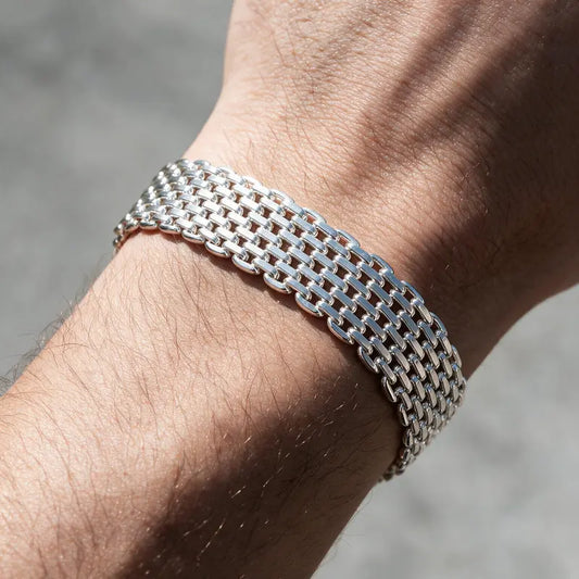 Wide silver woven mesh chain bracelet worn on the wrist