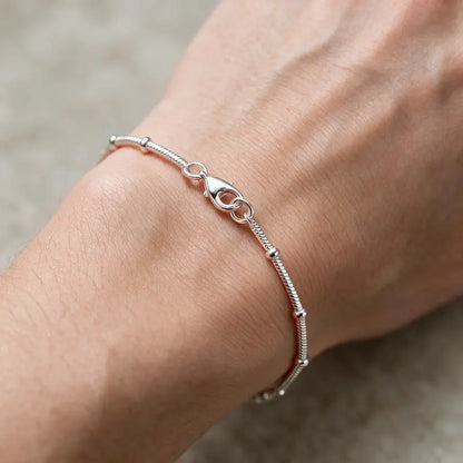 Silver snake chain bracelet with bead stations worn on the wrist