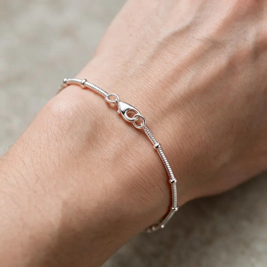 Silver snake chain bracelet with bead stations worn on the wrist
