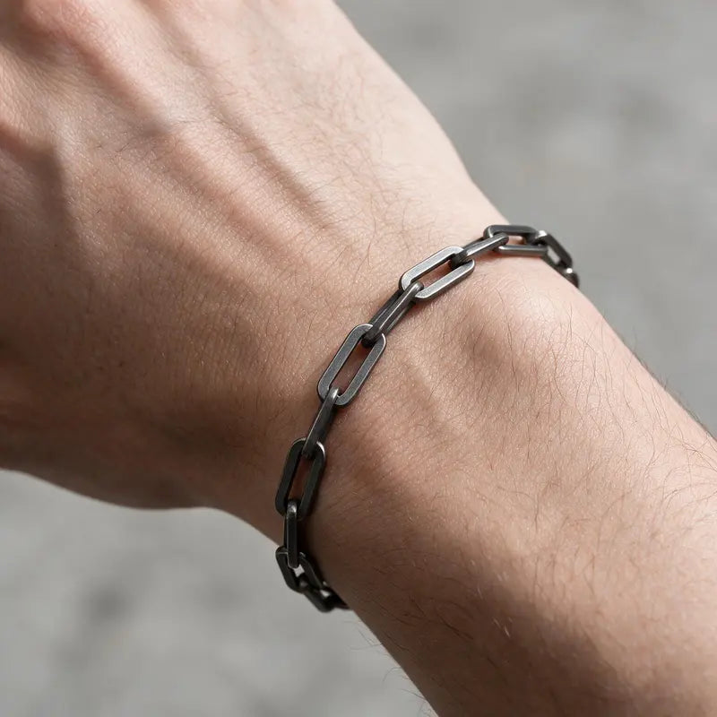 Thin dark oxidized stainless steel paperclip link chain bracelet worn on the wrist