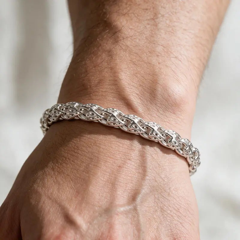 Bold silver woven herringbone-style chain bracelet worn on the wrist