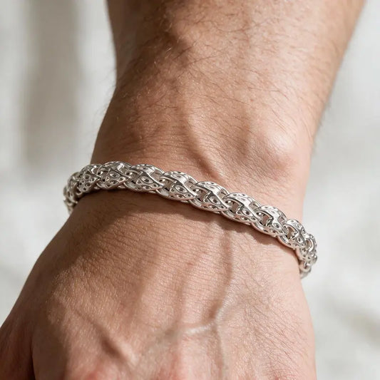 Bold silver woven herringbone-style chain bracelet worn on the wrist