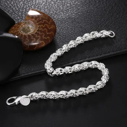 925 sterling silver woven herringbone chain bracelet displayed beside a fossil shell
