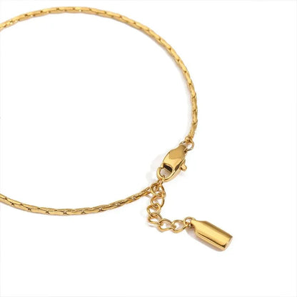 Close-up of the gold hammered wire bracelet's clasp and drop charm on a white background.