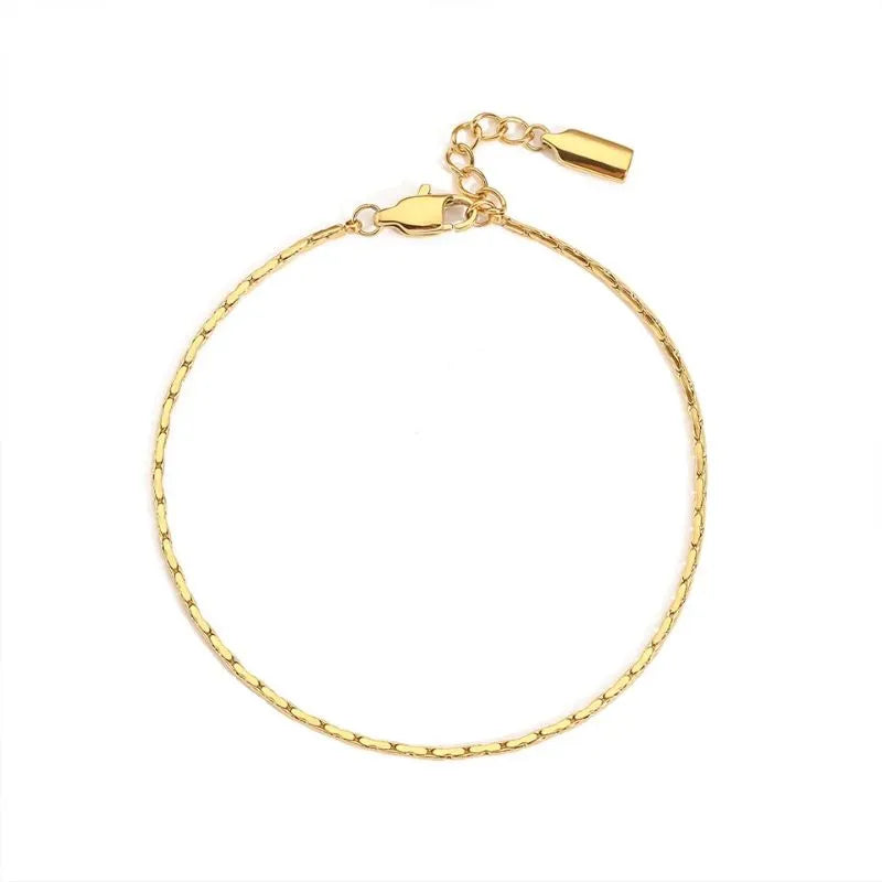 Gold hammered wire chain bracelet laid in a circle on a white background, with the lobster clasp and drop charm visible.