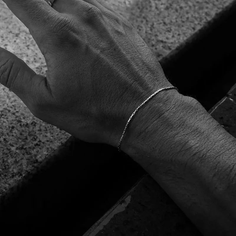Black-and-white photo of the silver-tone wire bracelet worn on the wrist, resting on stone steps.