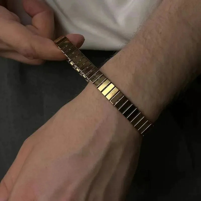 Fingers stretching the gold flexible bracelet open to demonstrate how it slips on and off the wrist