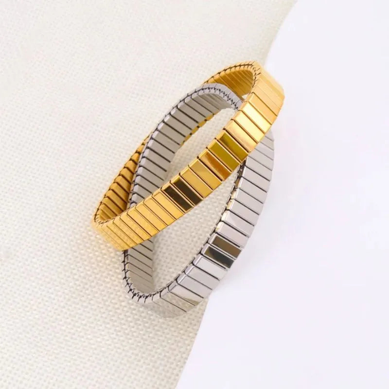 Gold and silver stretch bracelets crossed together on a white surface
