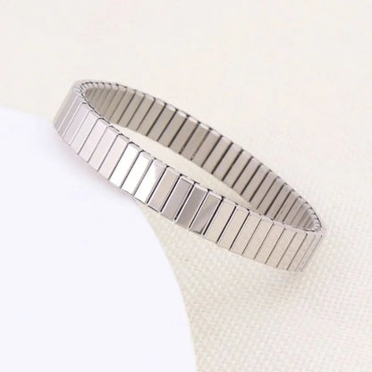 Silver stretch bracelet laid diagonally on a light cream textured surface