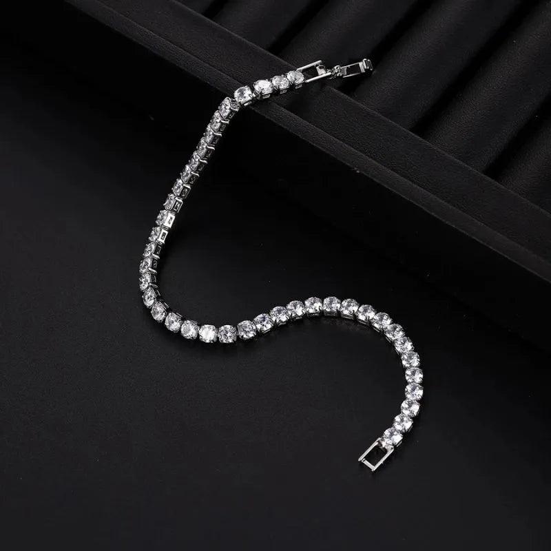 Silver tennis bracelet with clear stones laid in an S-curve on a black ribbed jewellery tray