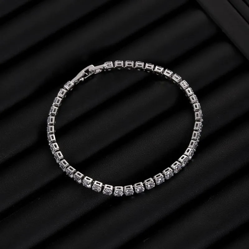 Silver tennis bracelet with clear stones laid in a circle on a black ribbed jewellery tray