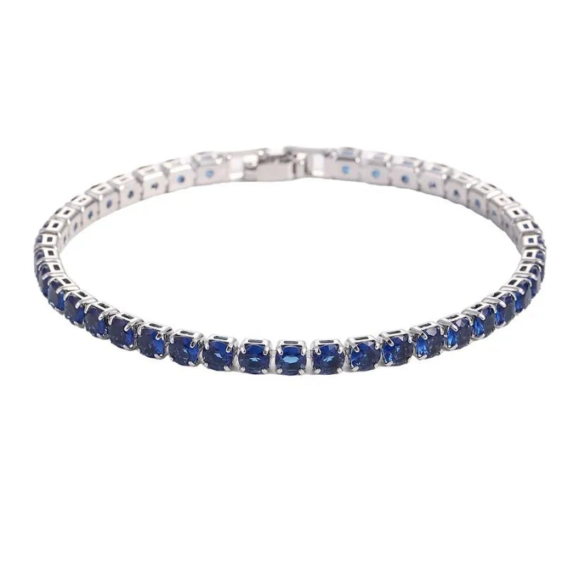 Tennis bracelet with dark blue sapphire-coloured stones in a silver setting, on a plain white background