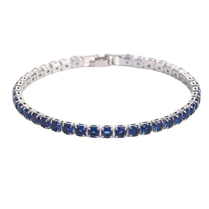 Tennis bracelet with dark blue sapphire-coloured stones in a silver setting, on a plain white background