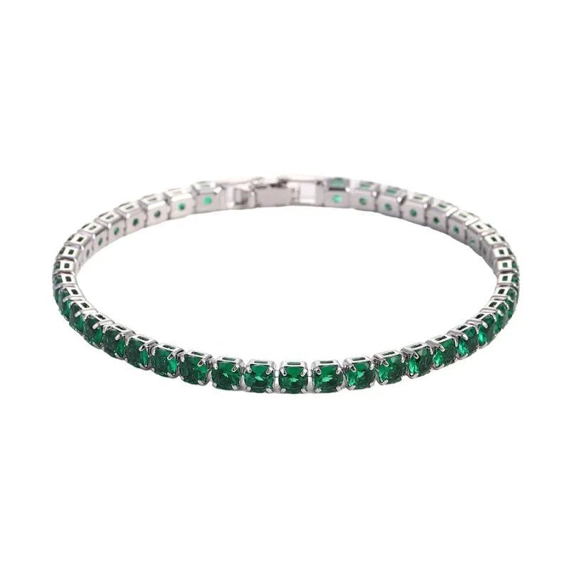 Tennis bracelet with green emerald-coloured stones in a silver setting, on a plain white background