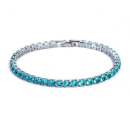 Tennis bracelet with turquoise-coloured stones in a silver setting, on a plain white background