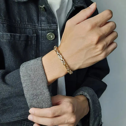 Gold Byzantine box-chain bracelet worn on the wrist, paired with a denim jacket outfit.