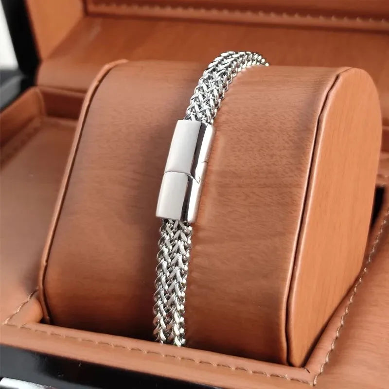 Silver wheat link chain bracelet with a matching clasp, displayed on a tan leather jewellery stand