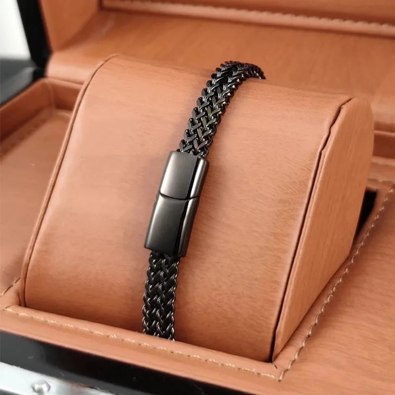 Black wheat link chain bracelet with a matching clasp, displayed on a tan leather jewellery stand