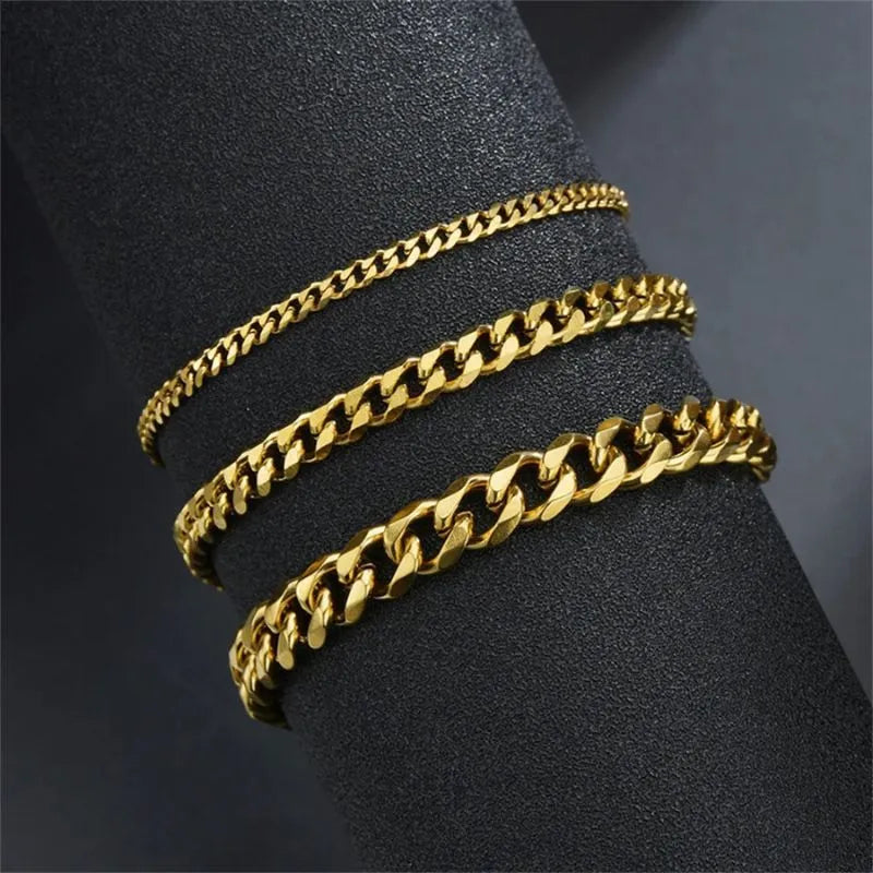 Three gold Cuban chain bracelets of increasing width draped around a black display cylinder, showing the range of available widths.
