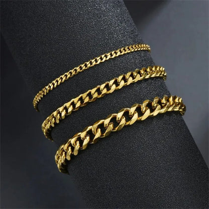 Three gold Cuban chain bracelets of increasing width draped around a black display cylinder, showing the range of available widths.