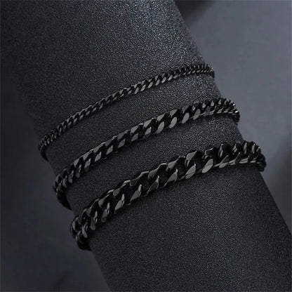 Three black-finish Cuban chain bracelets of increasing width draped around a black display cylinder, showing the range of available widths.