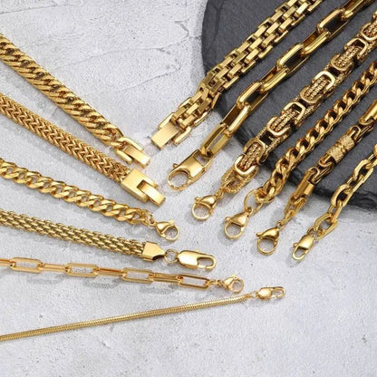 Close-up spread of gold chain bracelets on a stone slab showing each style's lobster clasp in detail