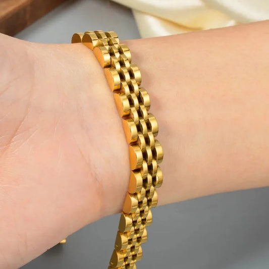 Close-up of a wrist wearing the gold watch link bracelet with a white fabric backdrop