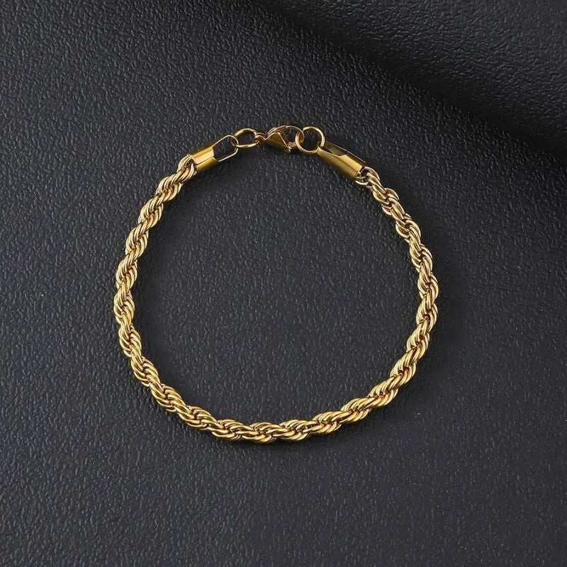 Gold twisted Singapore rope chain bracelet laid flat in a circle on a black textured surface, with the lobster clasp visible.