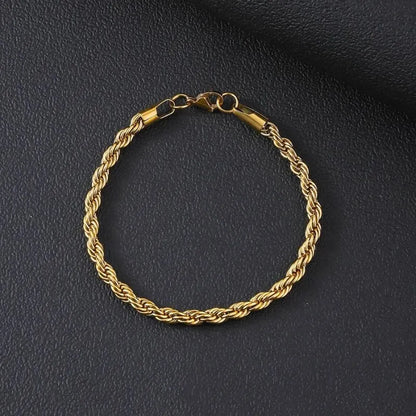 Gold twisted Singapore rope chain bracelet laid flat in a circle on a black textured surface, with the lobster clasp visible.