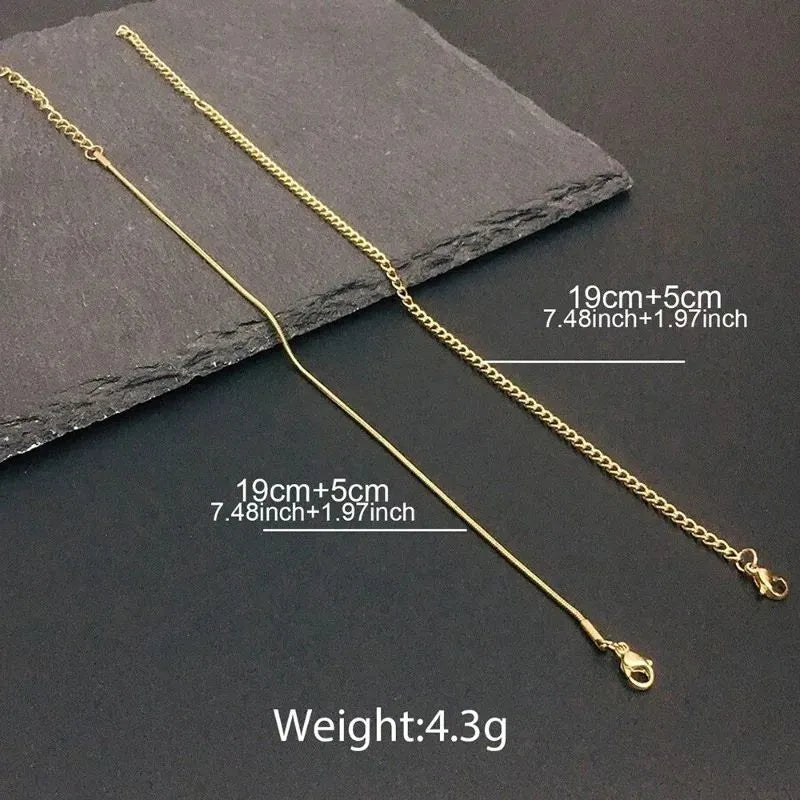 Two gold chains, a snake chain and a curb chain, laid diagonally on a dark slate surface, each labeled 19cm+5cm (7.48in+1.97in) with a total weight of 4.3g.