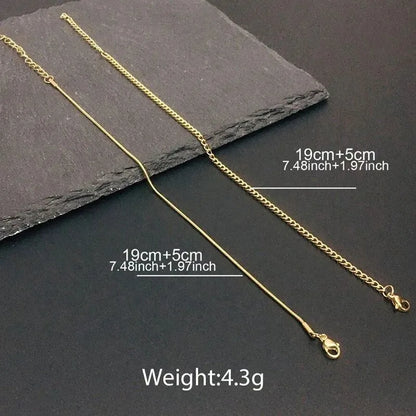 Two gold chains, a snake chain and a curb chain, laid diagonally on a dark slate surface, each labeled 19cm+5cm (7.48in+1.97in) with a total weight of 4.3g.