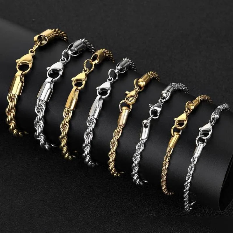 Multiple twisted rope chain bracelets in gold and silver draped diagonally over a black display stand, showing the range of colors and widths.