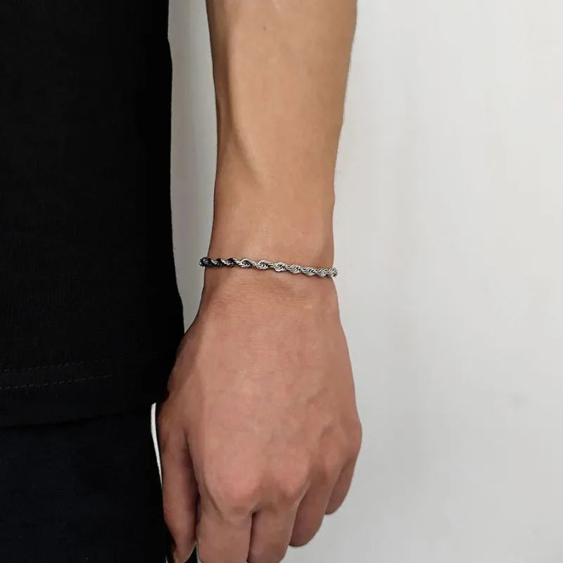 Two-tone dark and silver twisted rope chain bracelet worn on the wrist, side profile against a white background, shown in a slightly thicker width.