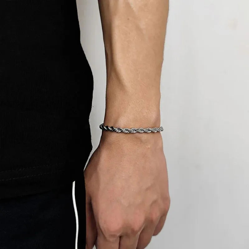 Thicker silver-tone twisted rope chain bracelet worn on the wrist, side profile against a white background.