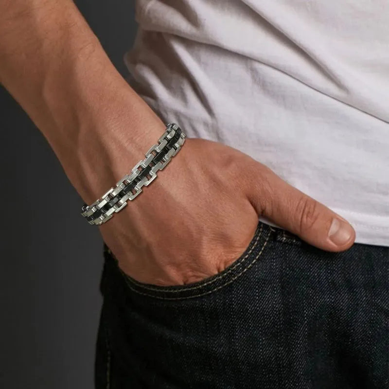 Two-tone silver and black watchband-link bracelet worn on the wrist, paired with a white t-shirt and dark denim jeans.