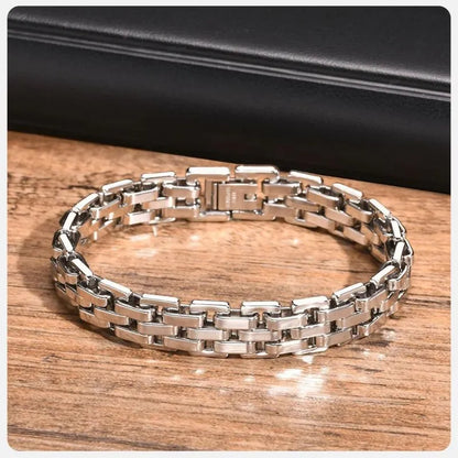 Silver watchband-link bracelet laid in an oval on a wooden surface, with a dark box prop in the background.