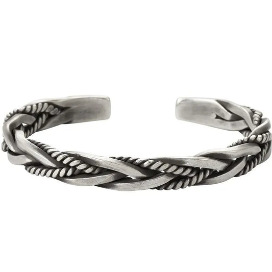 Silver open-cuff bracelet with a braided rope-and-flat-band twist pattern, laid on a plain white background.
