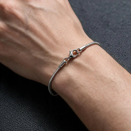 Silver thin snake chain bracelet worn on a man's wrist.