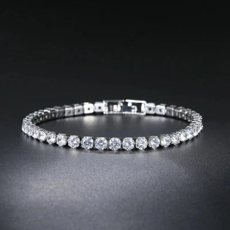 Silver tennis bracelet with round cubic zirconia stones laid in an oval on a dark gradient background, fold-over clasp visible.