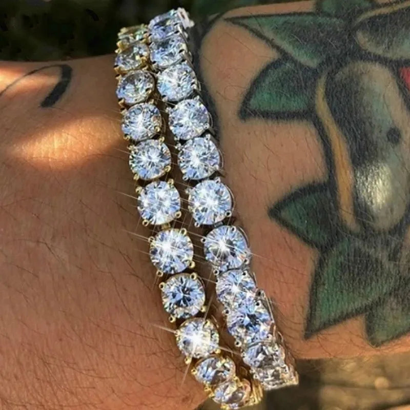 Two tennis bracelets with brilliant round stones worn stacked on a tattooed wrist, close-up.