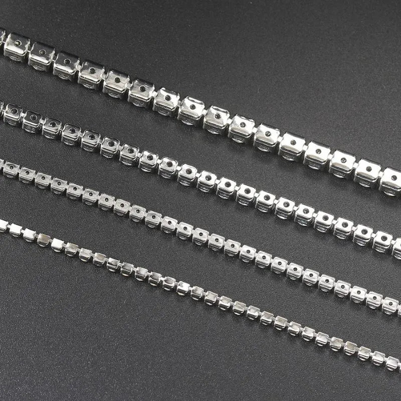 Reverse view of four silver tennis bracelets showing the prong-setting undersides, on a dark textured surface.