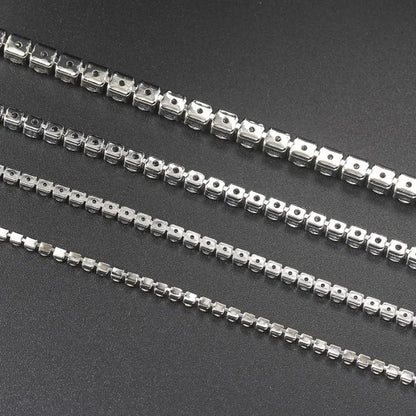 Reverse view of four silver tennis bracelets showing the prong-setting undersides, on a dark textured surface.