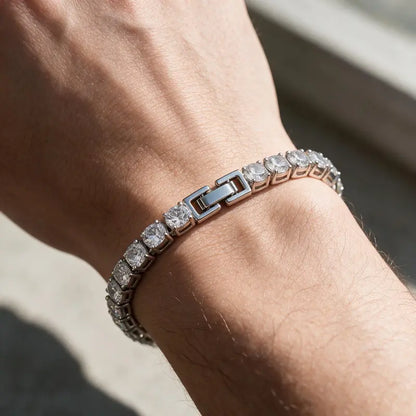 Silver tennis bracelet with round cubic zirconia stones, worn on a man's wrist.