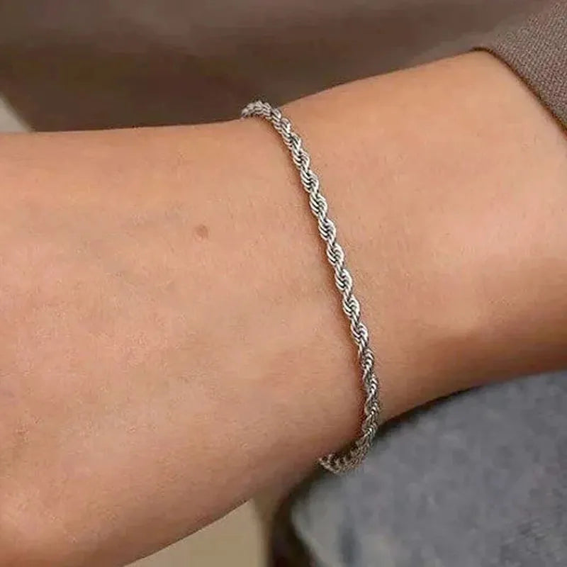 Silver twisted rope chain bracelet worn on the wrist, paired with a grey sweater sleeve.