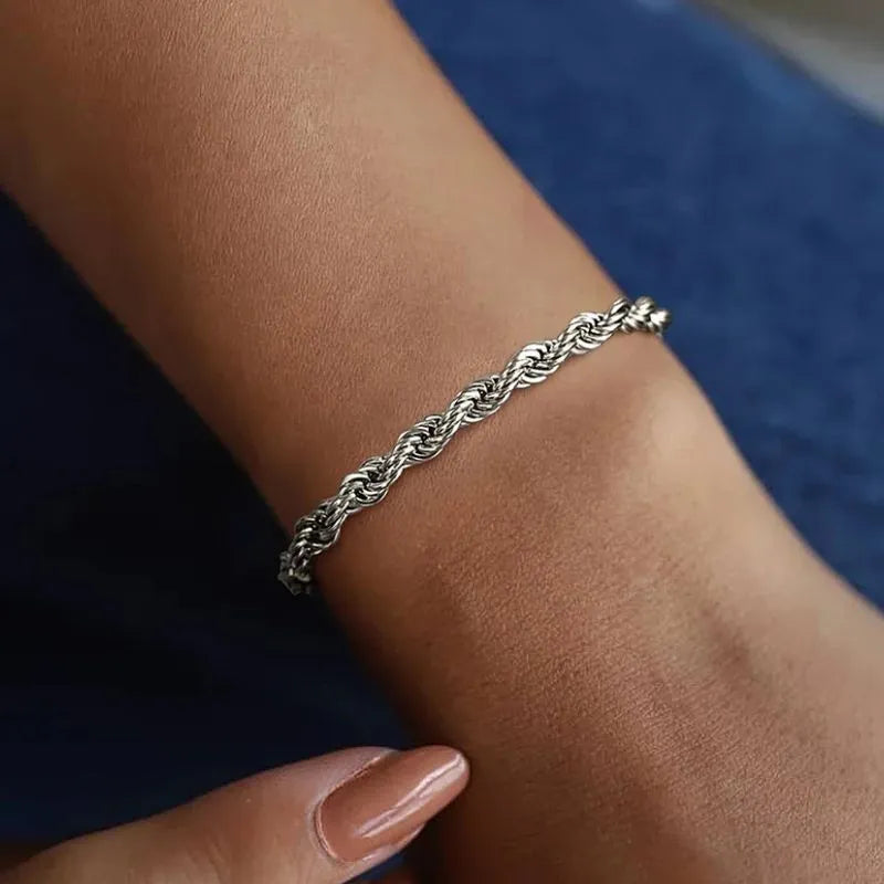 Silver twisted rope chain bracelet worn on the wrist, close-up against a navy fabric background.