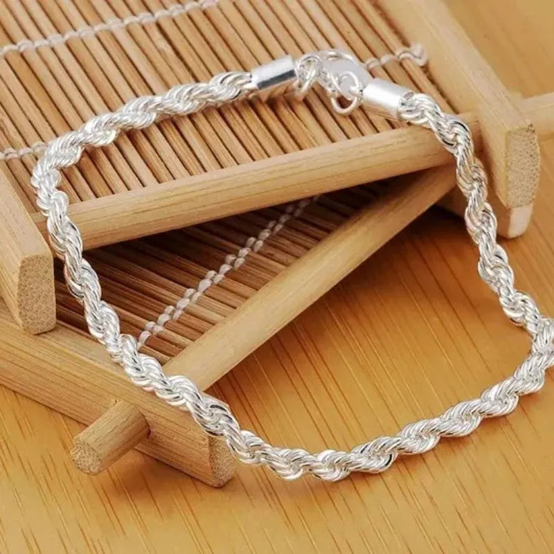 Silver twisted rope chain bracelet laid diagonally over a bamboo display prop.