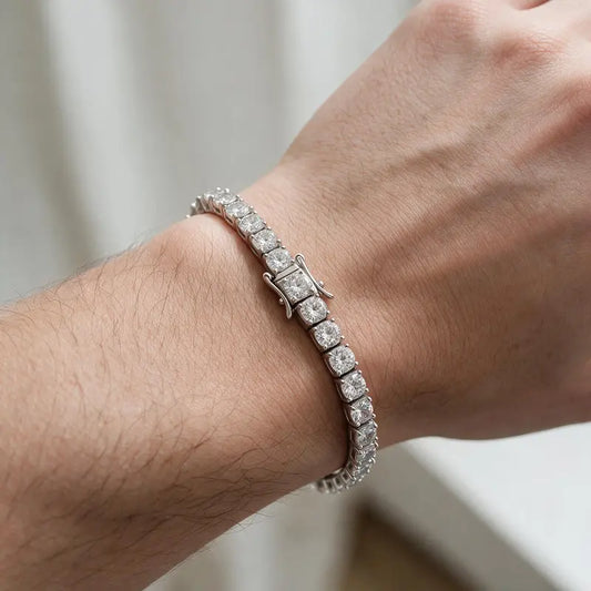 Silver tennis bracelet with round cubic zirconia stones, worn on a man's wrist.
