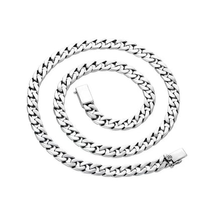 Long silver Cuban-link chain coiled in a spiral on a plain white background.