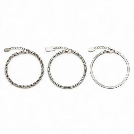Three silver chain bracelets — twisted rope, snake chain, and flat blade chain — laid out separately with clasp and extension chain closure detail and pendant tags, on a plain white background.